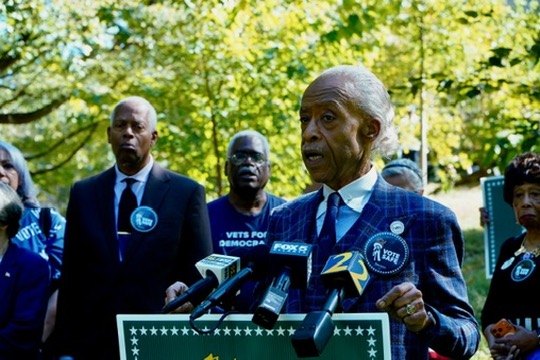 Rev. Al Sharpton at the Vote Safe podium with Congressman Hank Johnson and Vets for Democracy behind him