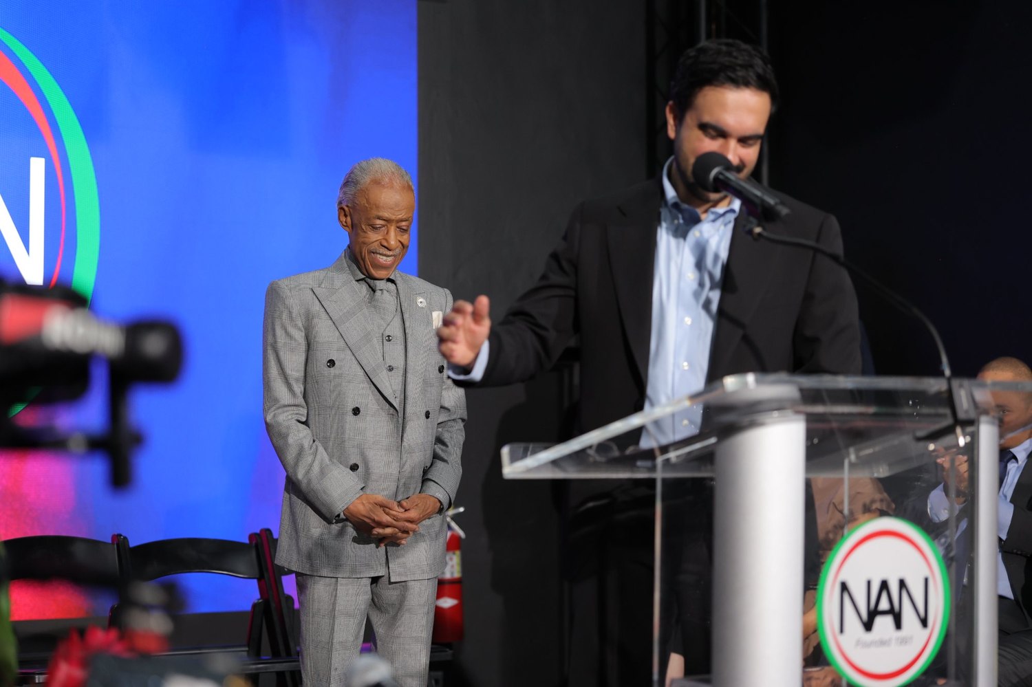Mayor Zohran Mamdani speaks at the House of Justice podium as Rev. Al Sharpton looks on