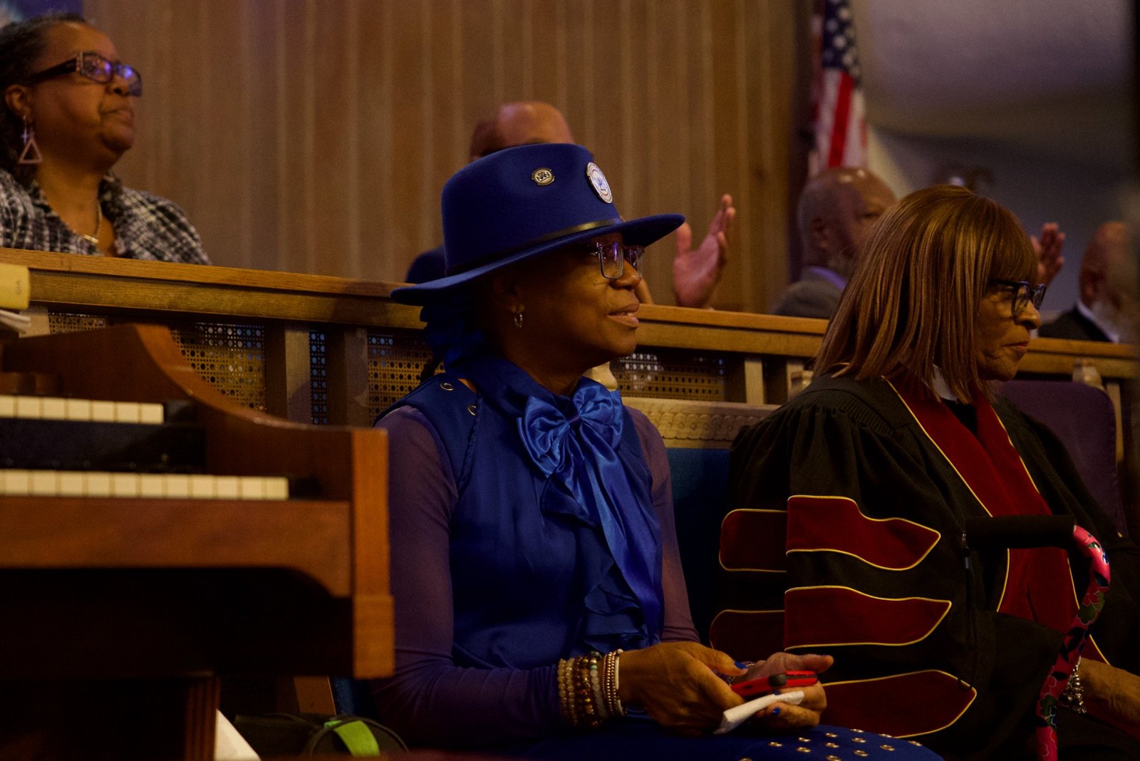 A member of the National Action Network in a blue NAN hat listens from the pews