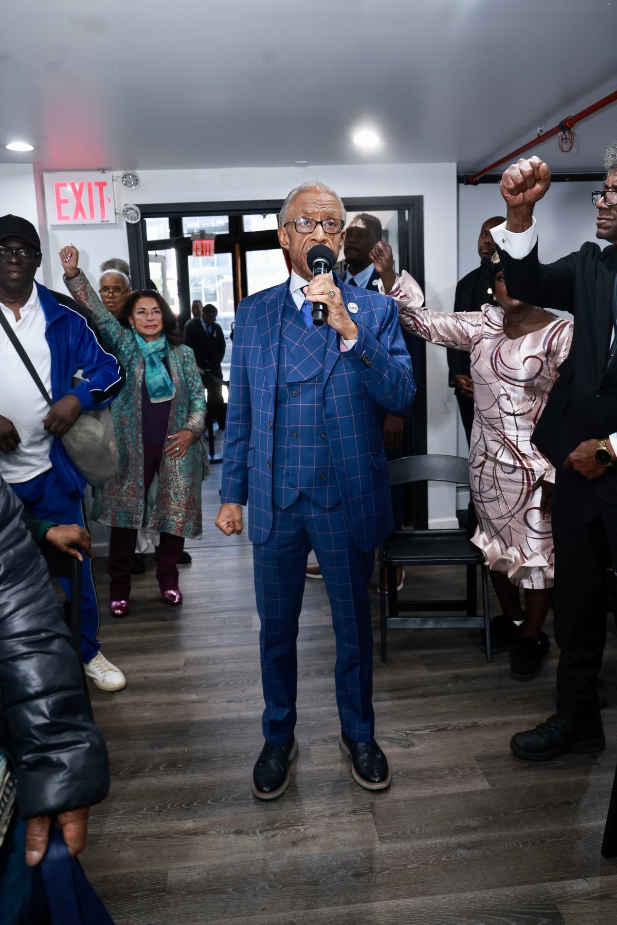 Rev. Al Sharpton with the microphone in the middle of the House of Justice as the crowd raises their fists