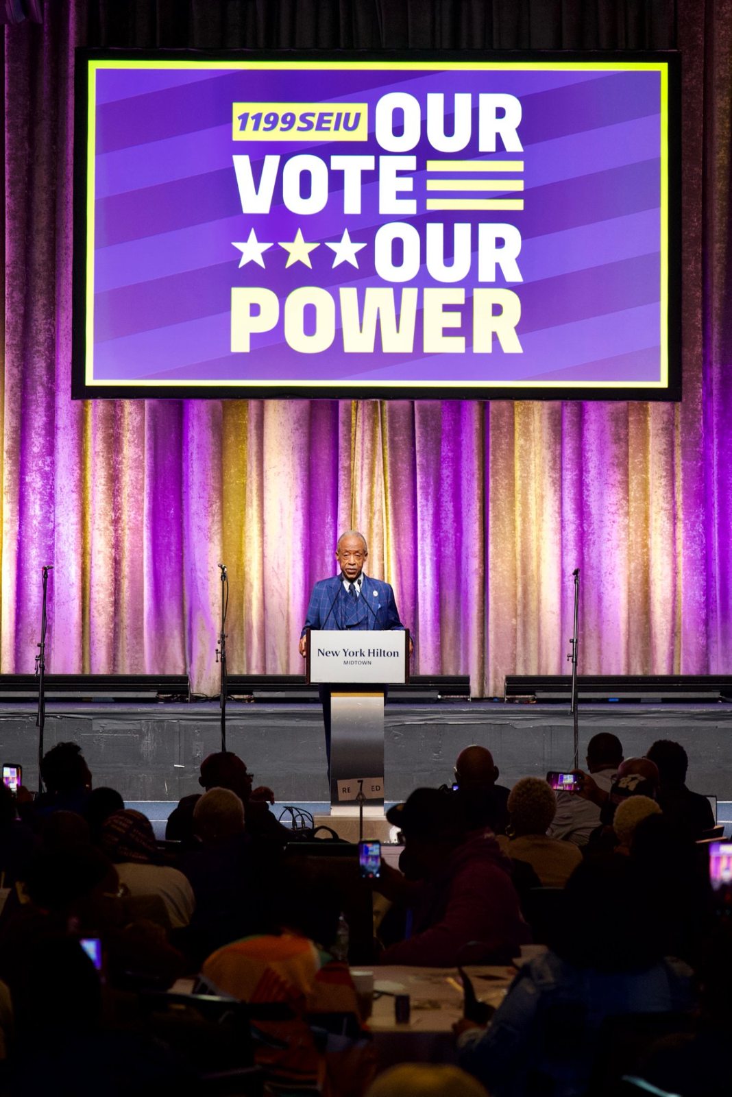 Rev. Al Sharpton on stage beneath the Our Vote, Our Power screen at the New York Hilton Midtown